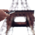 A traveller using a smartphone while standing near a well-known landmark, illustrating on-the-go mobile searches during travel.