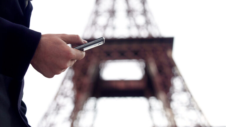Mobile-Friendly Design: Why It Matters for Tourists on the Move A traveller using a smartphone while standing near a well-known landmark, illustrating on-the-go mobile searches during travel.
